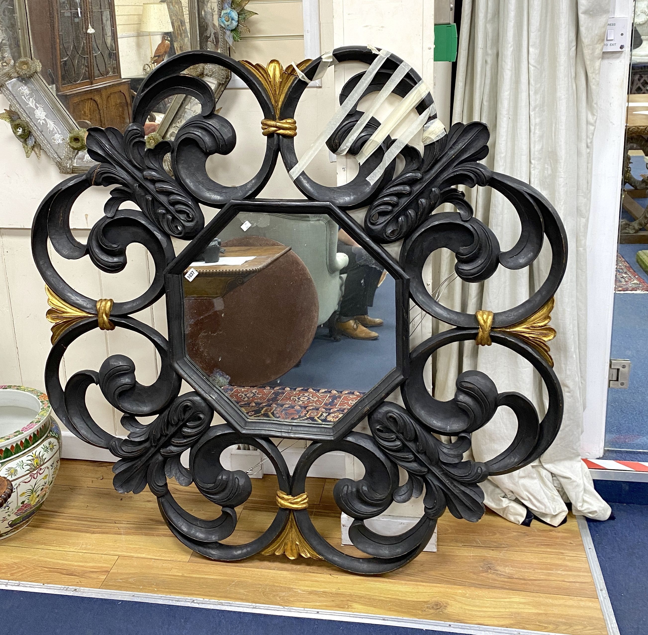 A large black painted and parcel gilt Italian style wall mirror, with octagonal plate, width 143cm, plate 57cm